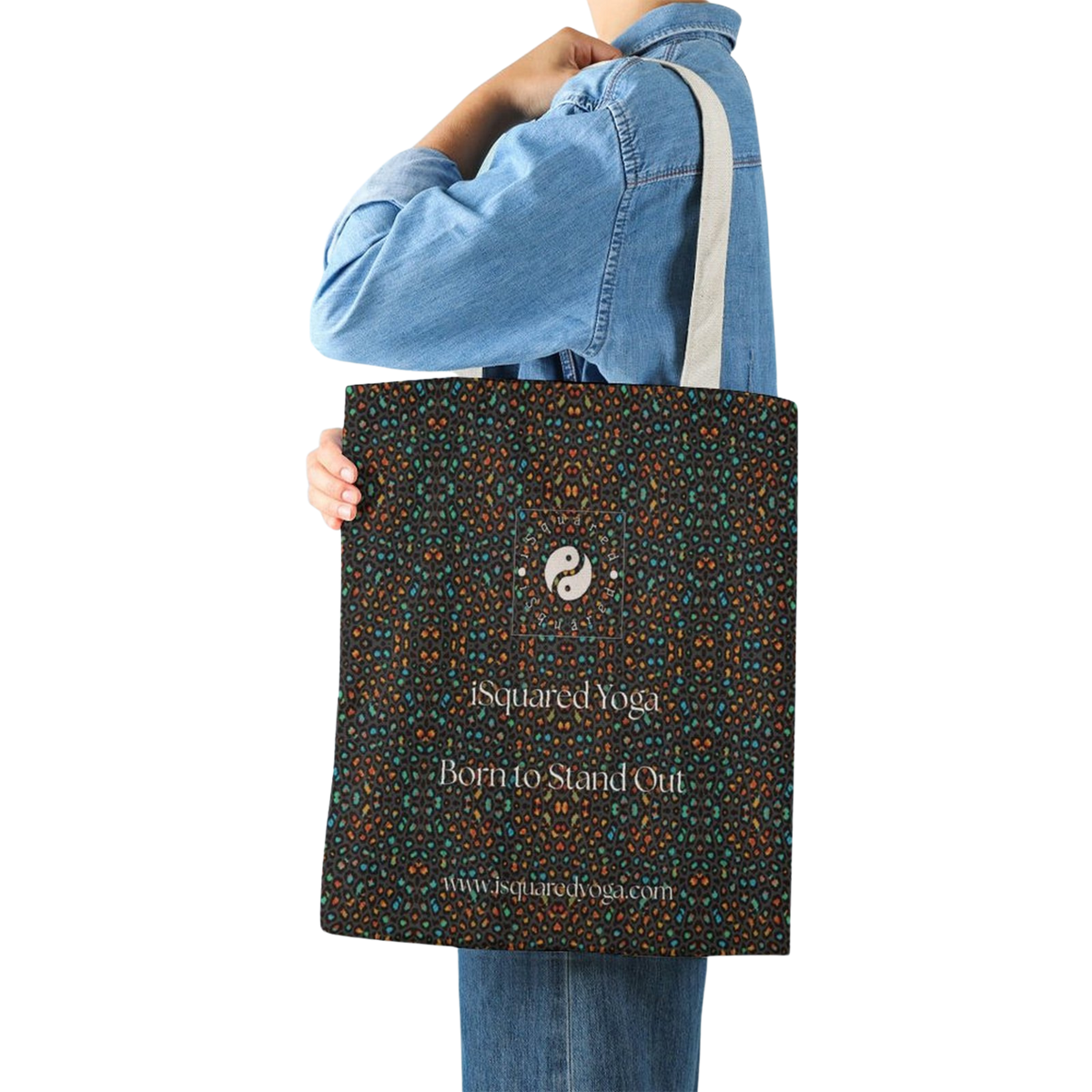 Stylish tote bag in dark colors with leopards spots, held by a person wearing a denim jacket. Features a logo and text.