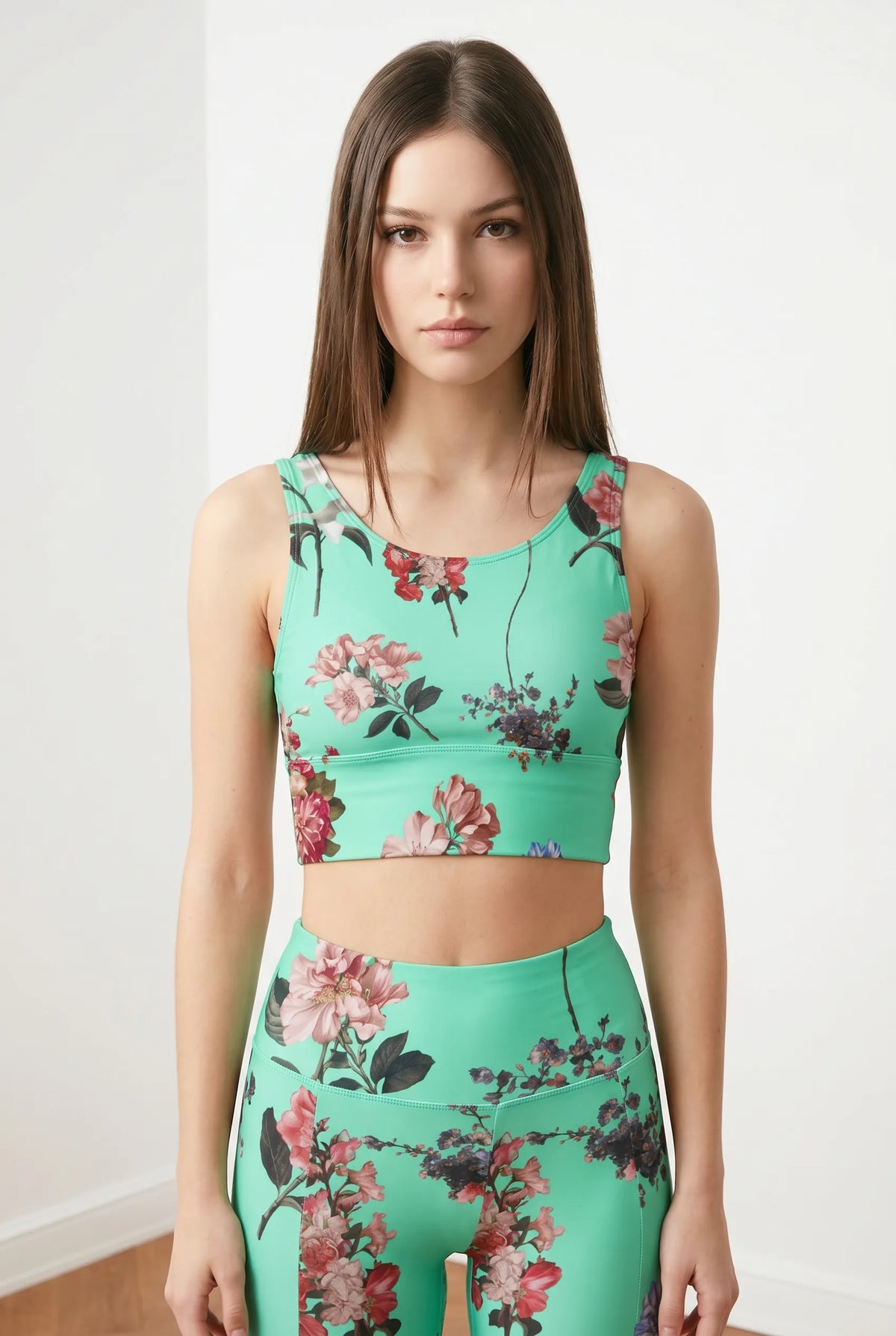 Cropped floral print top in vibrant turquoise, featuring thick straps and a U-back design, worn with matching leggings.
