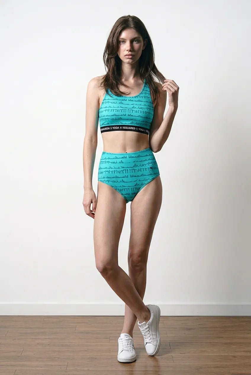 Turquoise hot yoga bikini set featuring a cropped top and high-waisted bottoms with black branding, worn by a model.