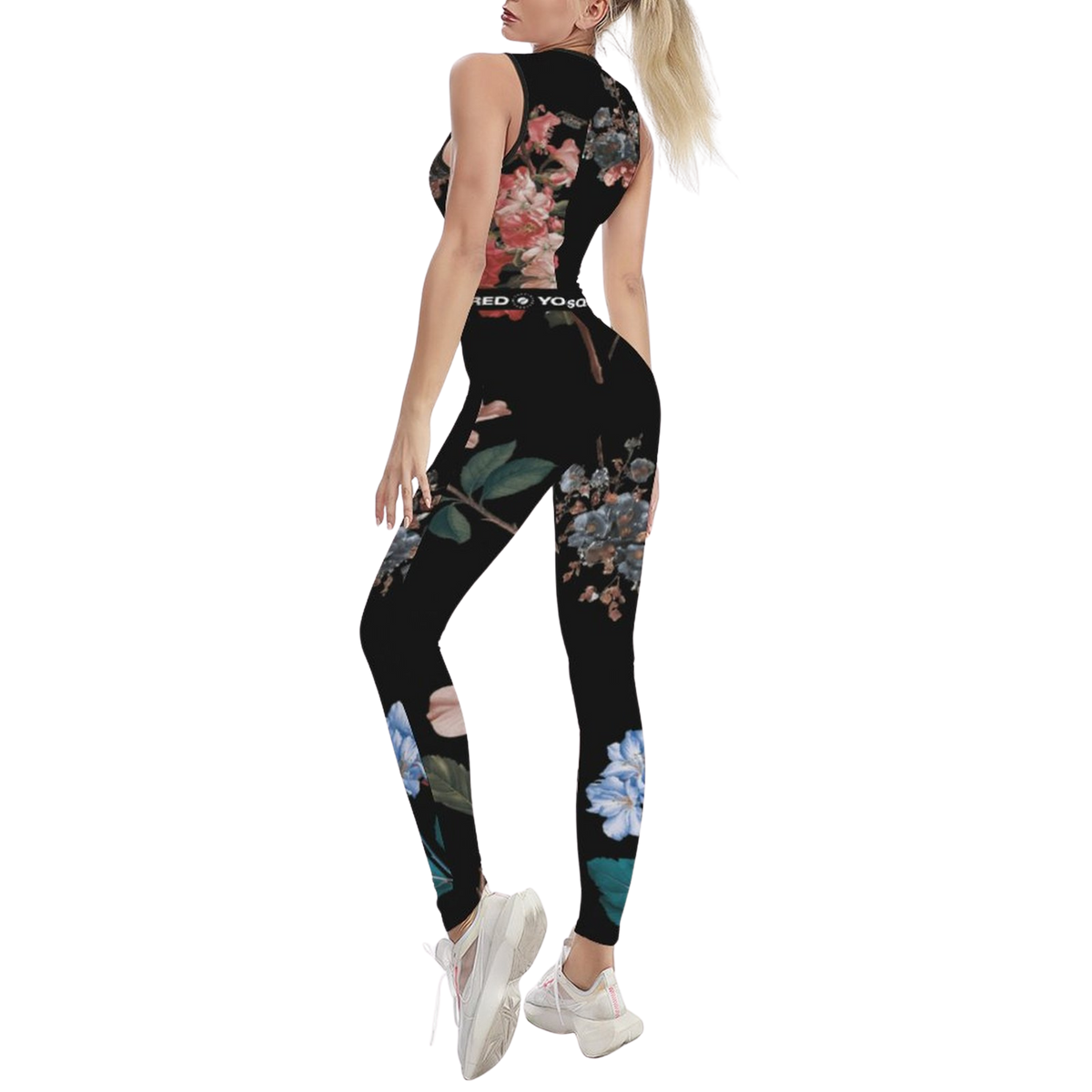 Sleeveless black jumpsuit featuring a colorful botanical print, body-hugging fit, paired with white athletic shoes.