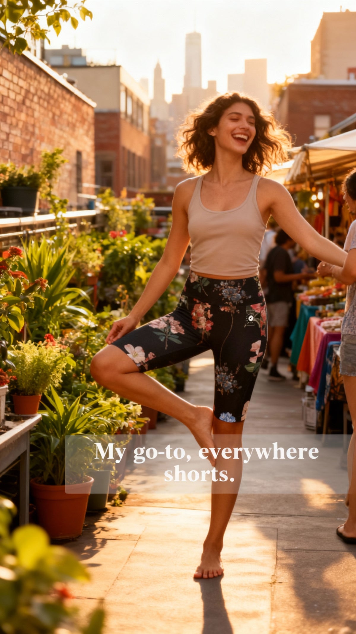 High-waisted, biker-length shorts in a floral print with dark background, paired with a light tank top, worn outdoors.