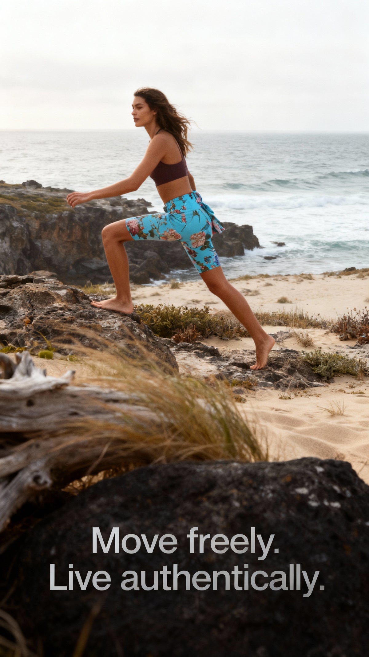 High-waisted iSquared Maureen Shorts in vibrant turquoise with floral print, worn by a model climbing rocks barefoot.
