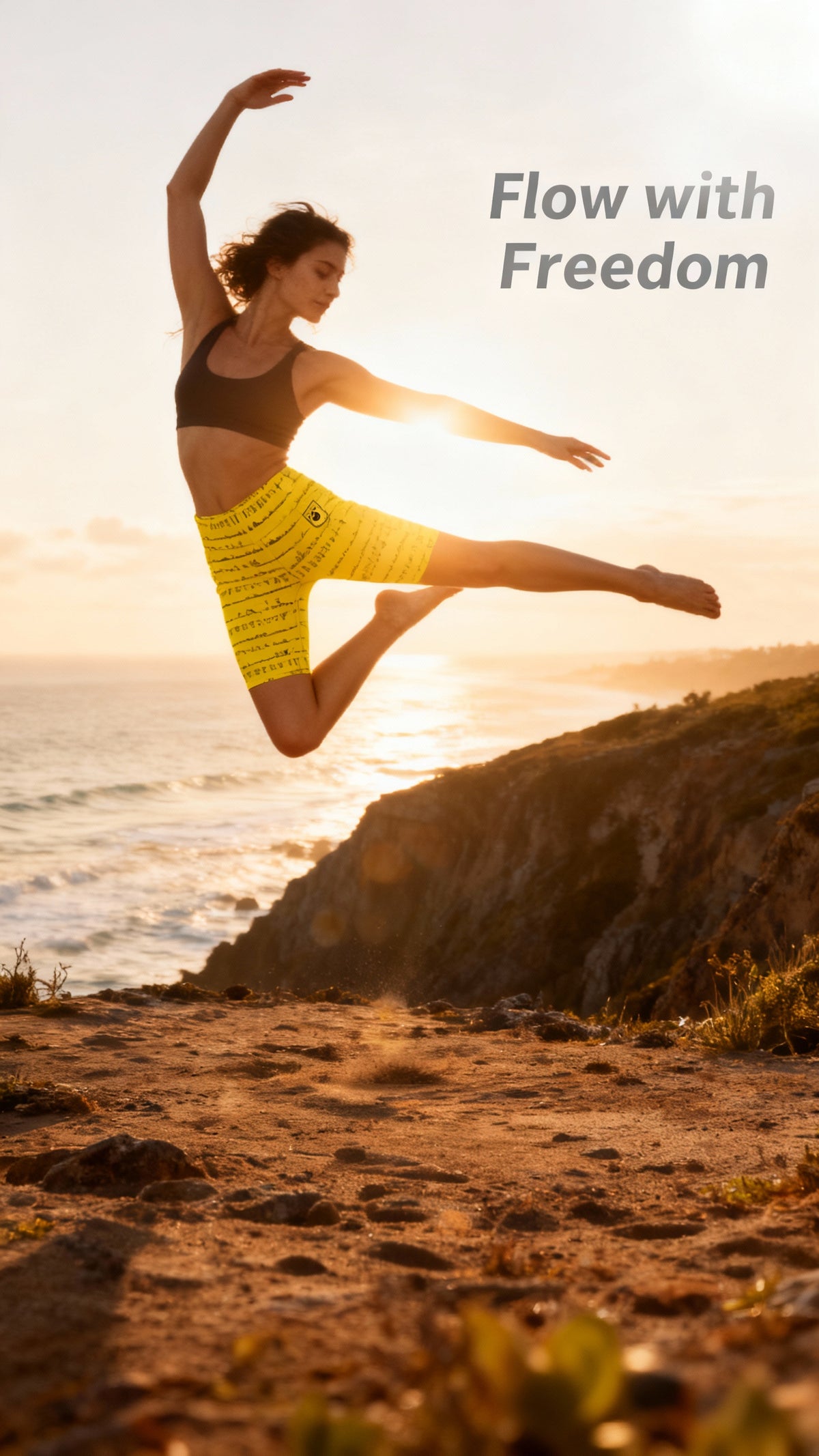 A woman leaps joyfully by the ocean, wearing bright yellow iSquared Maureen Shorts with a high waist and fit that enhances movement.
