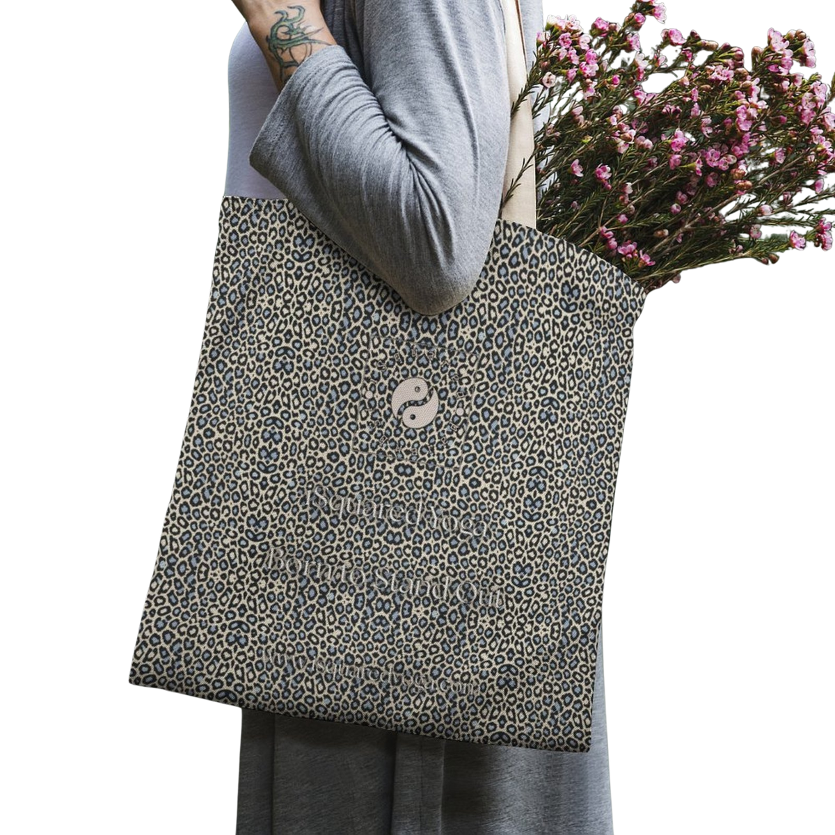 Tote bag featuring a wild leopard print design in beige and black, carried by a model with flowers inside.