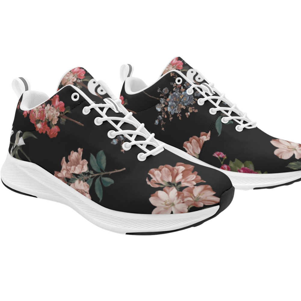 Black athletic sneakers featuring a botanical floral print in pink, white, and blue hues, with white laces and soles.